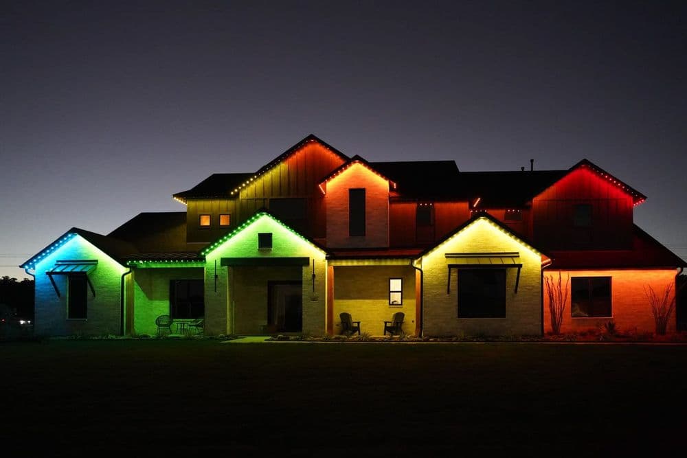 Modern house illuminated with colorful LED lights at dusk, showcasing vibrant exterior design.
