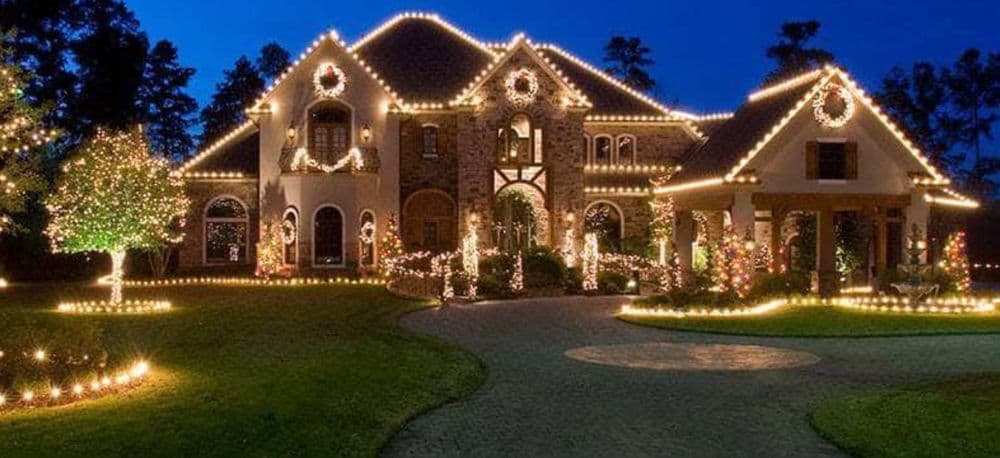 Beautifully decorated luxury home lit with festive Christmas lights at night.